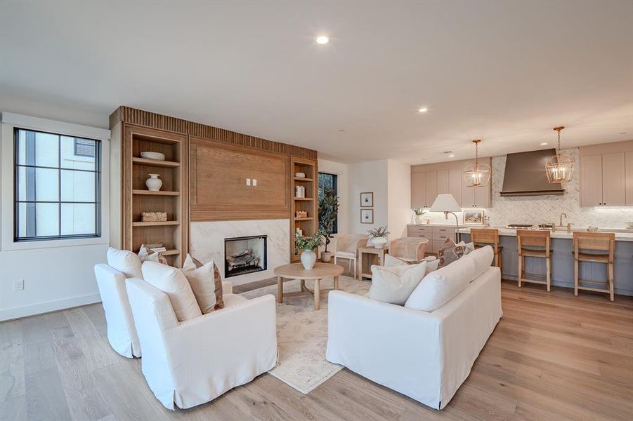 Living area with a premium fireplace, light wood-style flooring, recessed lighting, and a chandelier Living area with a premium fireplace, light wood-style flooring, recessed lighting, and a chandelier