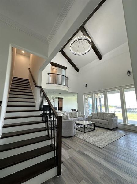 Living area featuring high vaulted ceiling, stairway, a chandelier, beamed ceiling, and wood finished floors Living area featuring high vaulted ceiling, stairway, a chandelier, beamed ceiling, and wood finished floors