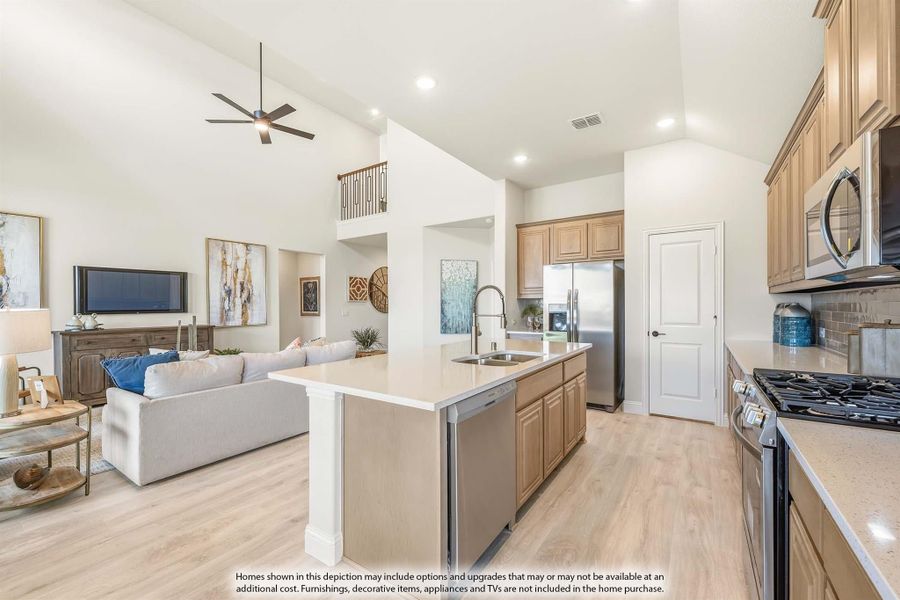 Open-concept kitchen with island, stainless steel appliances, and light wood cabinets overlooking a living room with vaulted ceiling.