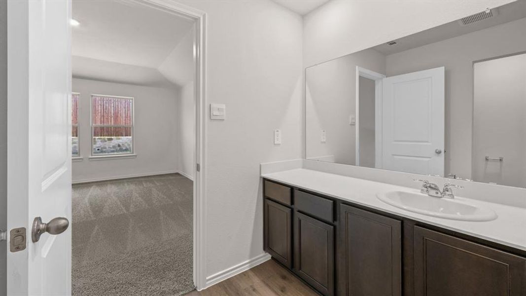 Bathroom vanity featuring a built-in sink with chrome fixtures, a spacious countertop, and dark wood-finish cabinetry