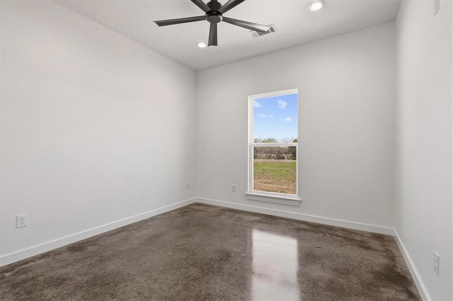 This room features a window providing views of the surrounding land, a ceiling fan, and recessed lighting
