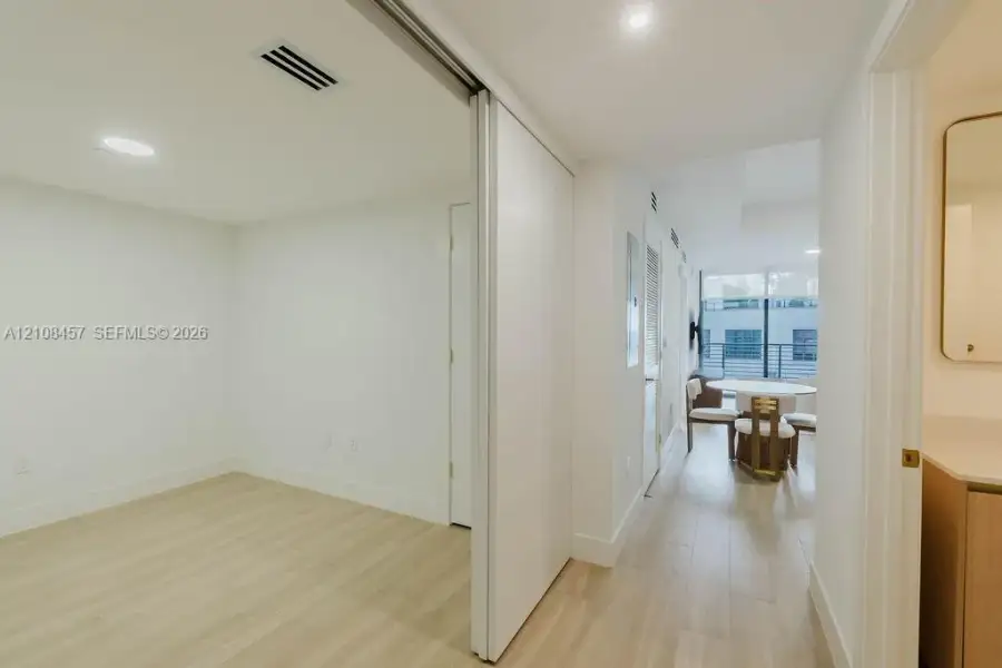 Interior space featuring wood-finish flooring, recessed lighting, and a large sliding door with a mirror finish Interior space featuring wood-finish flooring, recessed lighting, and a large sliding door with a mirror finish