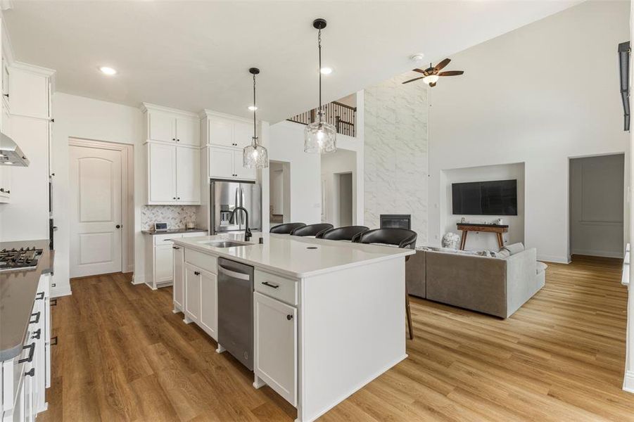 Kitchen featuring appliances with stainless steel finishes, ceiling fan, a towering ceiling, white cabinetry, and light wood-style floors Kitchen featuring appliances with stainless steel finishes, ceiling fan, a towering ceiling, white cabinetry, and light wood-style floors