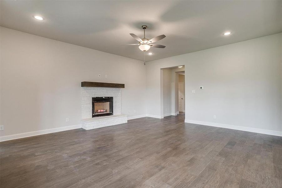 Unfurnished living room featuring ceiling fan, dark hardwood / wood-style flooring, and a fireplace