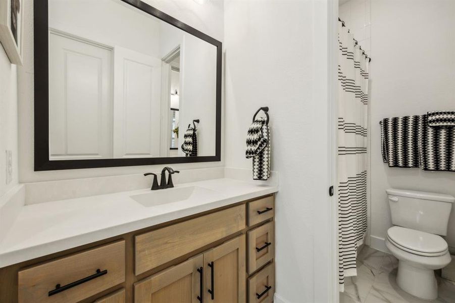 Full bath featuring marble finish flooring, toilet, vanity, and baseboards