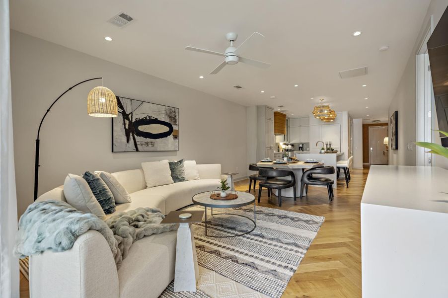 Bright, open living area with rich hardwood flooring extends to a contemporary kitchen.