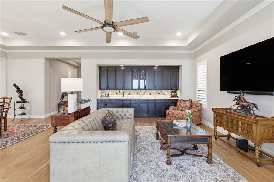 Grand Great Room anchored by an Impressive Built-in Bar designed for Effortless Entertaining. A Wall of Three-Panel Sliding Glass Doors opens to the Covered Outdoor Living Pavilion showcasing Panoramic Golf Course and Territorial Views.