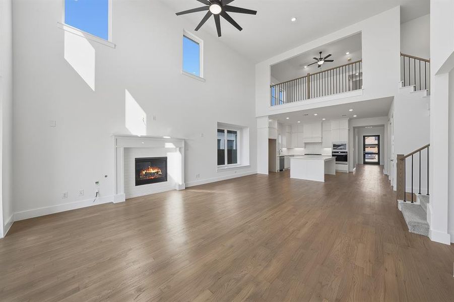 Unfurnished living room with a glass covered fireplace, ceiling fan, dark wood-style flooring, recessed lighting, and stairs Unfurnished living room with a glass covered fireplace, ceiling fan, dark wood-style flooring, recessed lighting, and stairs