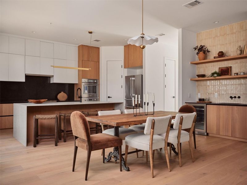 Dining space with light wood-type flooring, wine cooler, and bar