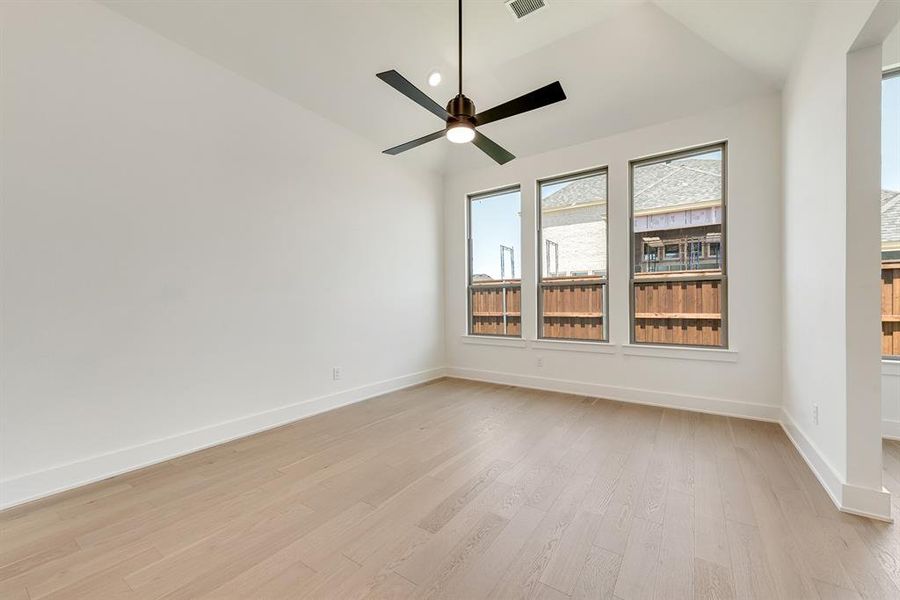 Unfurnished room with lofted ceiling, light wood-style flooring, ceiling fan, and recessed lighting Unfurnished room with lofted ceiling, light wood-style flooring, ceiling fan, and recessed lighting