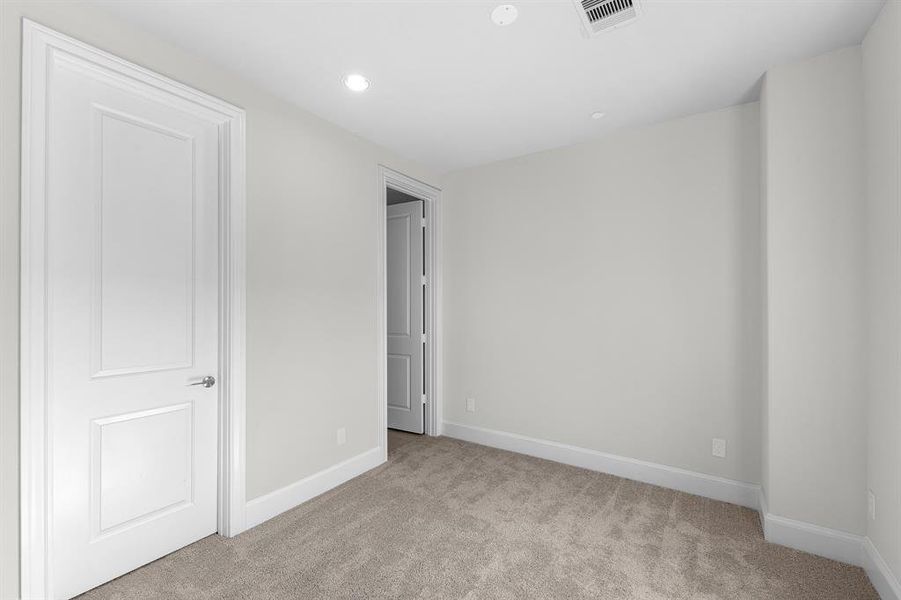 Recessed lighting offers ample illumination while contributing to the room's clean, modern aesthetic. This secondary bedroom also features a private ensuite bathroom, providing convenience and added privacy.