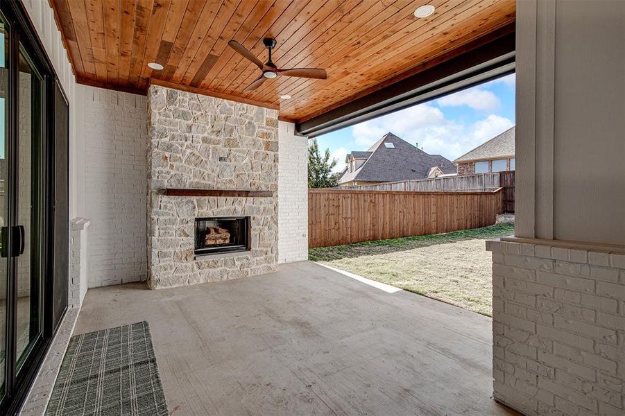 View of patio featuring an outdoor stone wood burning fireplace, ceiling fan, recessed lighting and cedar ceiling. View of patio featuring an outdoor stone wood burning fireplace, ceiling fan, recessed lighting and cedar ceiling.