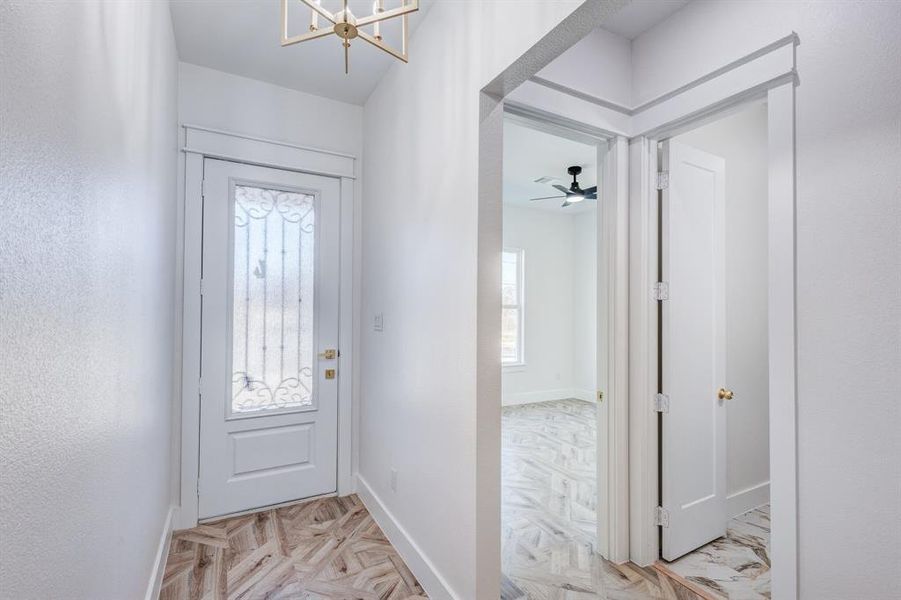 Entryway featuring ceiling fan with notable chandelier and light parquet floors