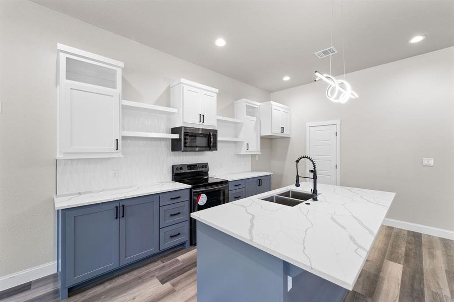 Kitchen featuring hardwood / wood-style floors, sink, white cabinetry, a center island with sink, and electric range