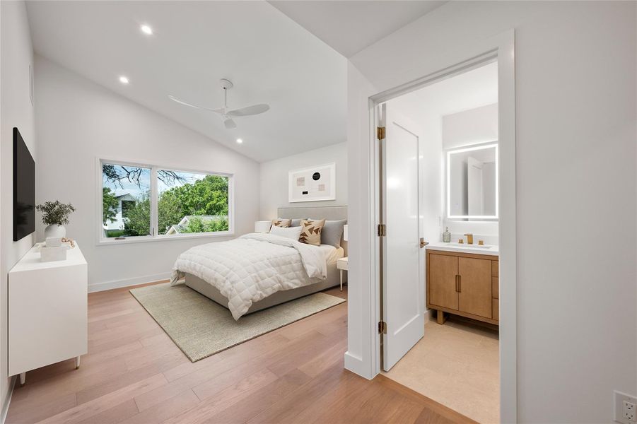 A restful primary bedroom retreat features a high vaulted ceiling, light wood flooring, and a private, well-appointed bathroom. A restful primary bedroom retreat features a high vaulted ceiling, light wood flooring, and a private, well-appointed bathroom.