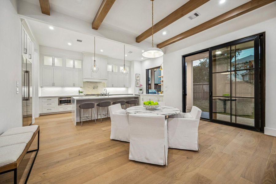 Breakfast Area with a 20" Wide Burnished Brass Bowl Pendant Light. There is a set of sliding doors that lead out the covered patio and a large yard with room enough for a pool.
