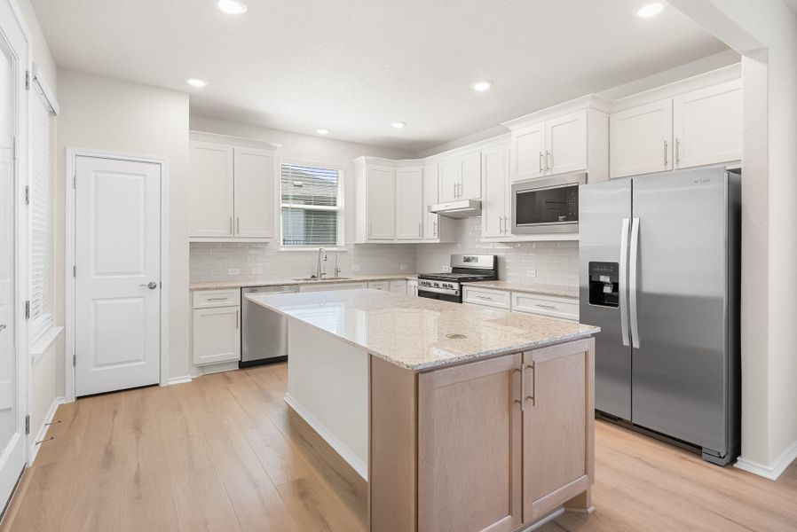 A well-lit kitchen featuring stainless steel appliances, granite countertops, and light wood flooring. A well-lit kitchen featuring stainless steel appliances, granite countertops, and light wood flooring.