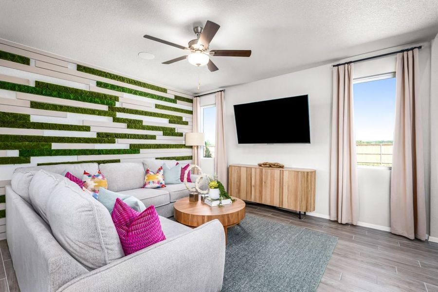 An image of living room with a white couch with bright pink pillows, tan coffee table, greenery, and a window with tan curtains. An image of living room with a white couch with bright pink pillows, tan coffee table, greenery, and a window with tan curtains.