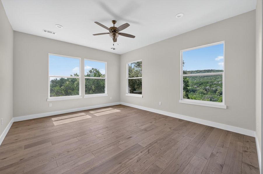 Gleaming hardwood floors and abundant windows framing scenic hill country views define this serene space.