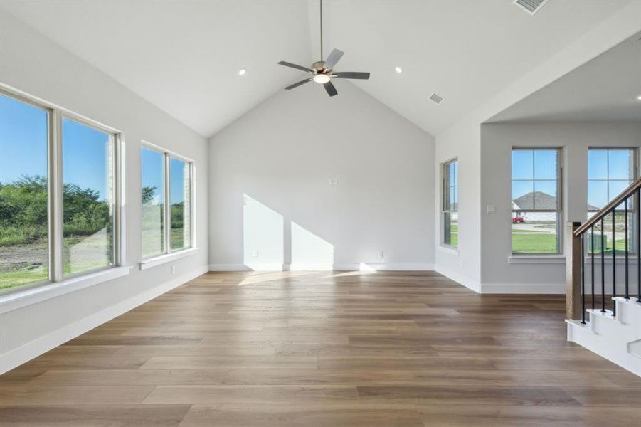 Unfurnished living room featuring hardwood / wood-style flooring, high vaulted ceiling, and ceiling fan