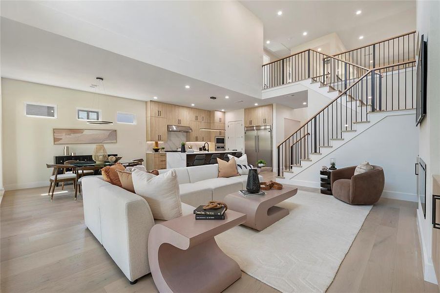 Living room with a towering ceiling, sink, and light wood-type flooring