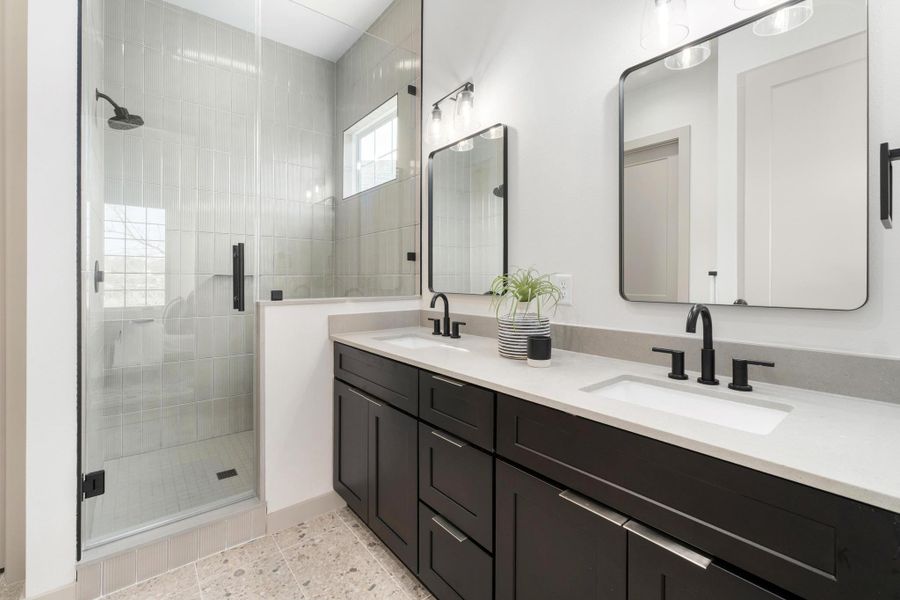 he primary retreat feels intentionally serene, with a spacious walk-in closet and a spa-inspired bathroom featuring dual vanities and an impressive walk-in shower wrapped in floor-to-ceiling tile.
