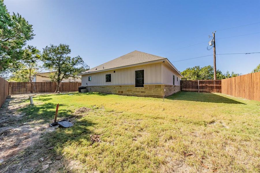 Back of property with a fenced backyard and a shingled roof