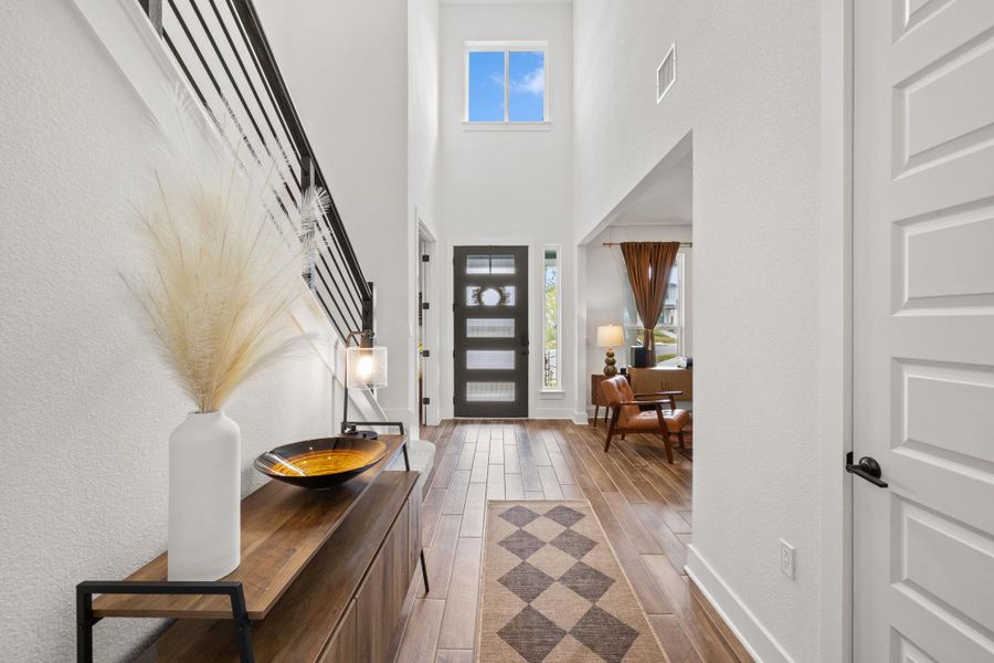 Foyer with tiled floors, stairway, and a towering ceiling
