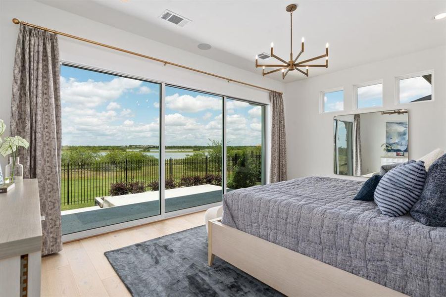 Bedroom with light wood-style flooring, a chandelier, access to outside, and a water view Bedroom with light wood-style flooring, a chandelier, access to outside, and a water view