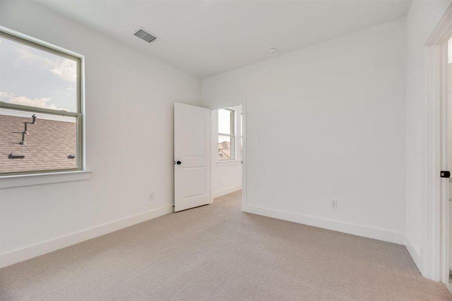 Unfurnished bedroom with multiple windows and carpet floors Unfurnished bedroom with multiple windows and carpet floors