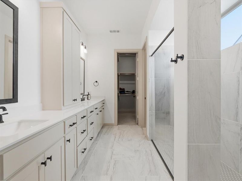 Bathroom featuring a dual vanity with white cabinetry and black hardware