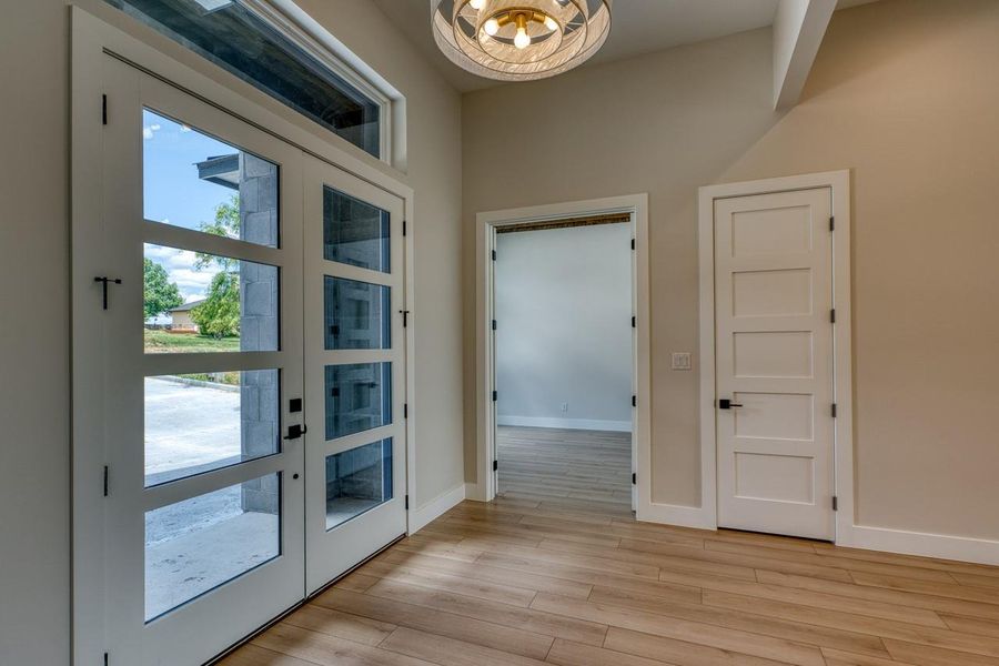 A welcoming entry features sleek glass panel doors and light wood-look flooring.