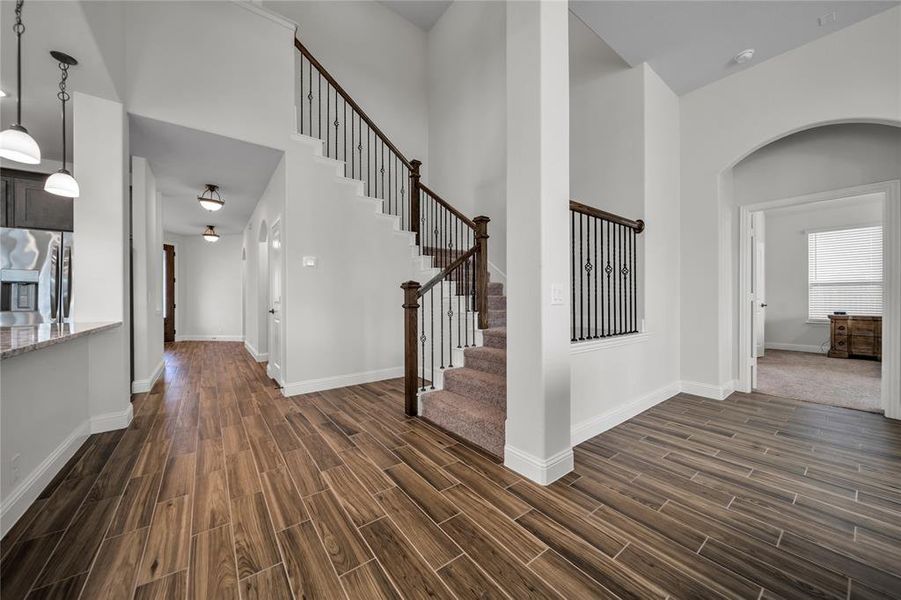 Foyer entrance featuring a high ceiling, arched walkways, wood tiled floors, and stairs Foyer entrance featuring a high ceiling, arched walkways, wood tiled floors, and stairs