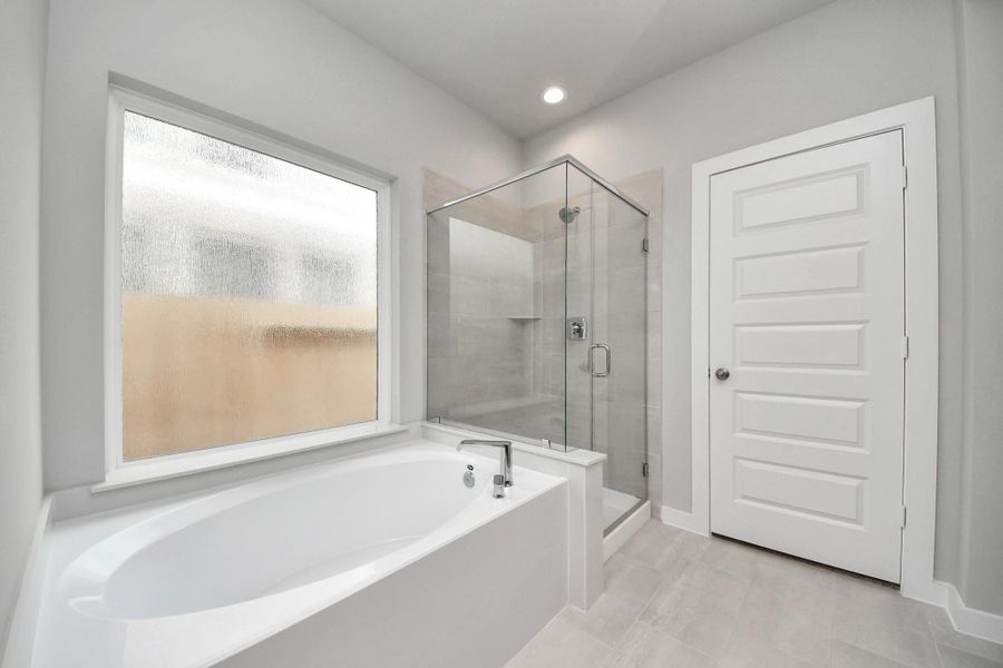 Indulge in a spa-like retreat within the confines of this primary bathroom. Delight in a spacious walk-in shower enveloped in stylish tile surround and unwind in a separate garden tub adorned with custom detailing.