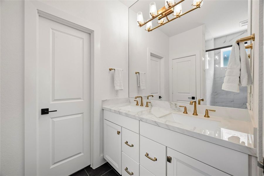 The primary bath is beautifully appointed with dual sinks, Quartz countertops and a full mirror accented by an integrated chandelier, adding an elegant designer touch to the space. The primary bath is beautifully appointed with dual sinks, Quartz countertops and a full mirror accented by an integrated chandelier, adding an elegant designer touch to the space.