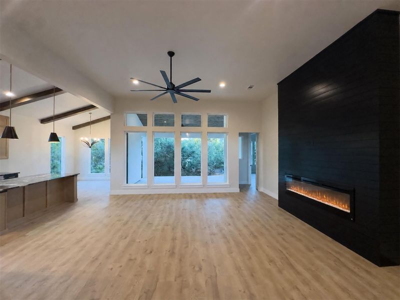 Warm wood flooring meets a striking dark fireplace wall in this open living area. Warm wood flooring meets a striking dark fireplace wall in this open living area.