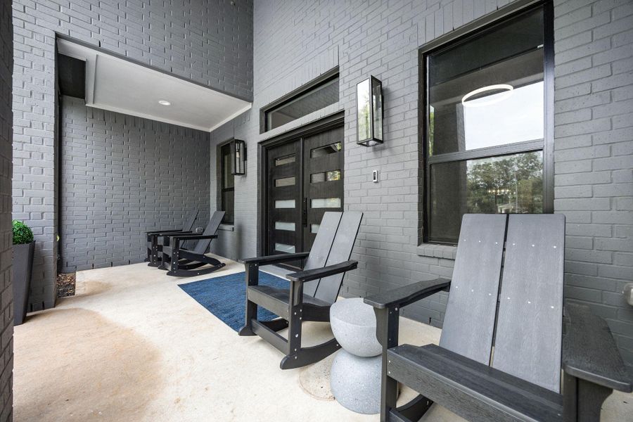 This photo showcases a modern front porch with sleek gray brick walls and a covered ceiling, creating an inviting space for relaxation and socializing. This photo showcases a modern front porch with sleek gray brick walls and a covered ceiling, creating an inviting space for relaxation and socializing.