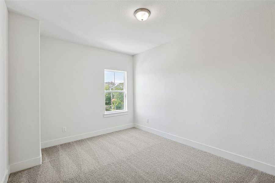 This room features light-colored carpeting, white walls, and a window providing natural light