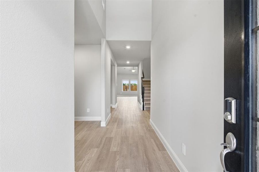 Bright entryway featuring light-colored flooring, recessed lighting, and a dark-colored security door with a smart lock