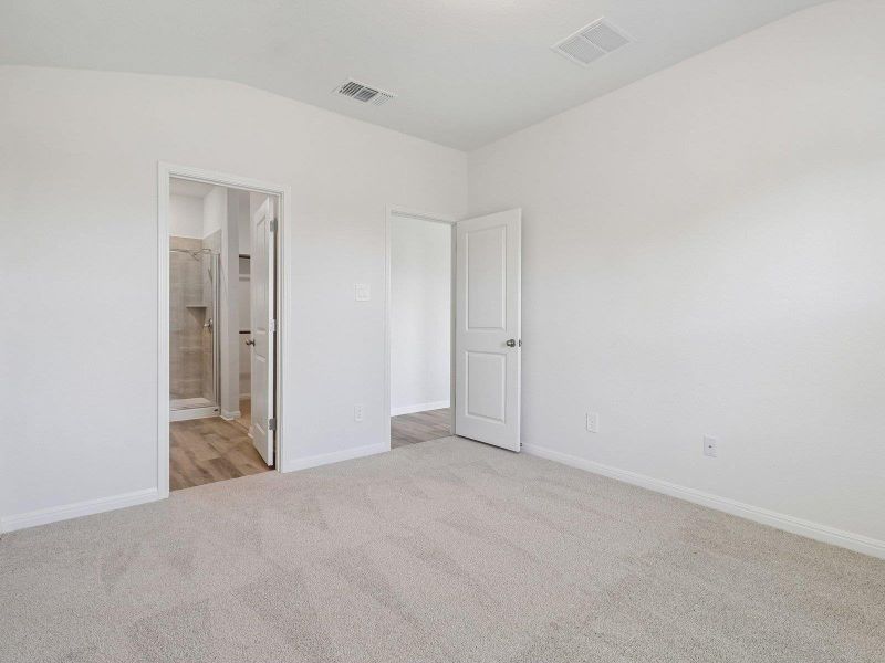 Plush carpeting and crisp white walls define this comfortable bedroom with an attached bathroom.