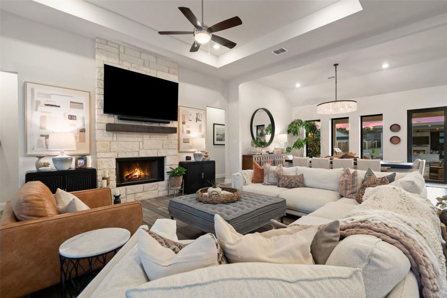 A grand living area features a natural stone fireplace and an open-concept layout leading to a dining space with abundant natural light. A grand living area features a natural stone fireplace and an open-concept layout leading to a dining space with abundant natural light.