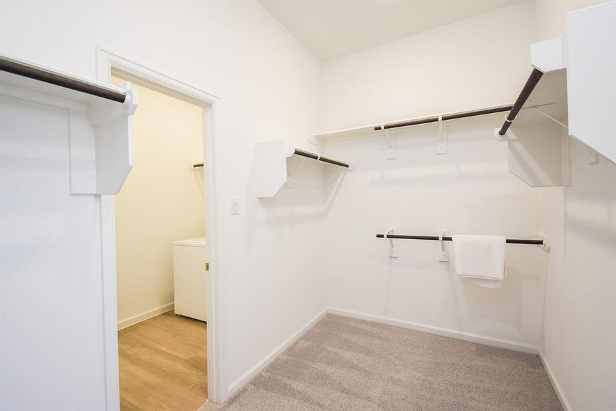 This is your amazing carpeted primary ensuite walk-in closet; with shelving, hanging rails, and floor space to store just about everything you own!