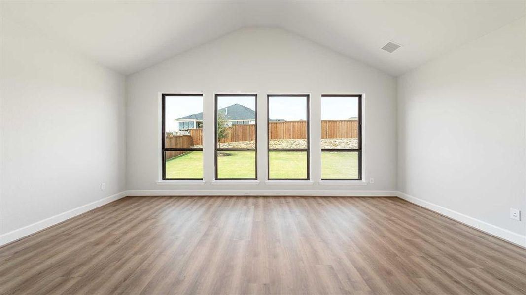 Spare room featuring plenty of natural light, high vaulted ceiling, and hardwood / wood-style floors