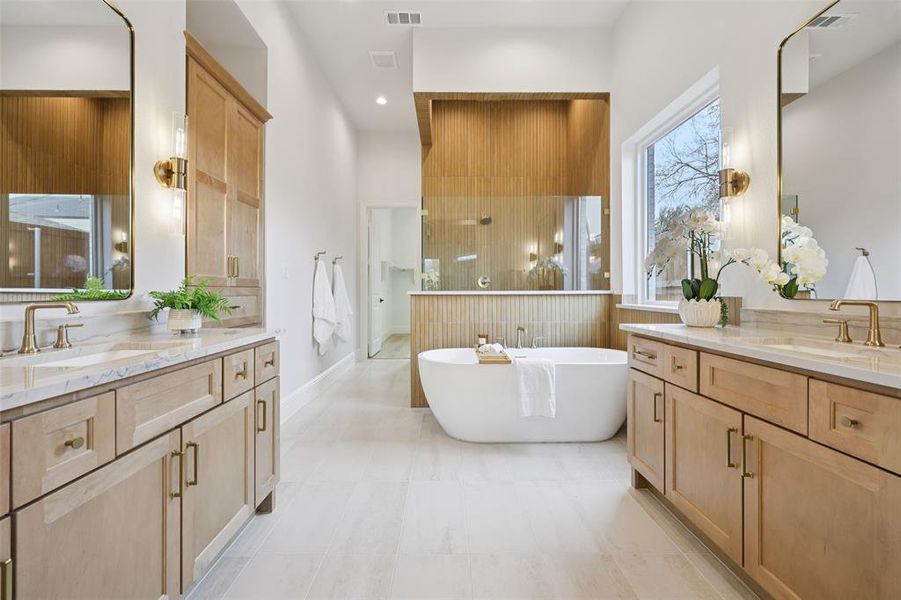 Full bathroom featuring two vanities and a freestanding bath