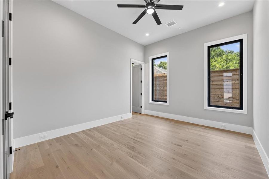 Light wood-finish flooring complements the neutral wall color in this room, featuring a modern black ceiling fan with recessed lighting Light wood-finish flooring complements the neutral wall color in this room, featuring a modern black ceiling fan with recessed lighting