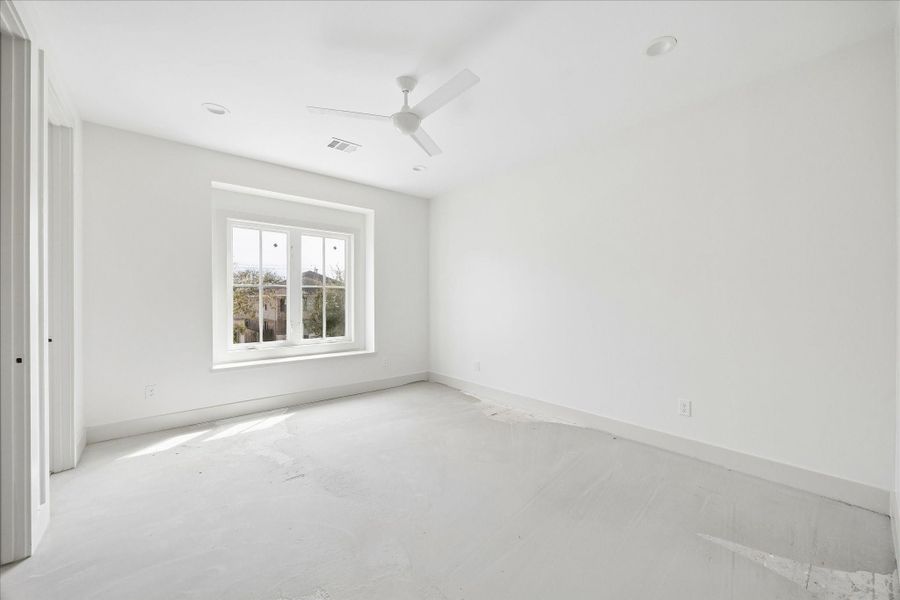 Bright secondary bedroom filled with natural light from a large window, creating a warm and inviting atmosphere. The clean, neutral palette and spacious layout offer flexibility for a variety of uses, whether as a guest room, nursery, or home office. High ceilings and recessed lighting enhance the open feel, while ample wall space allows for easy furniture placement and personalization.