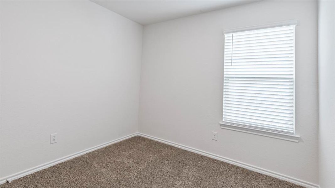 Spare room featuring dark carpet and baseboards