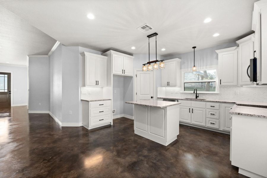 Kitchen featuring tasteful backsplash, concrete flooring, white cabinetry, a kitchen island, and recessed lighting