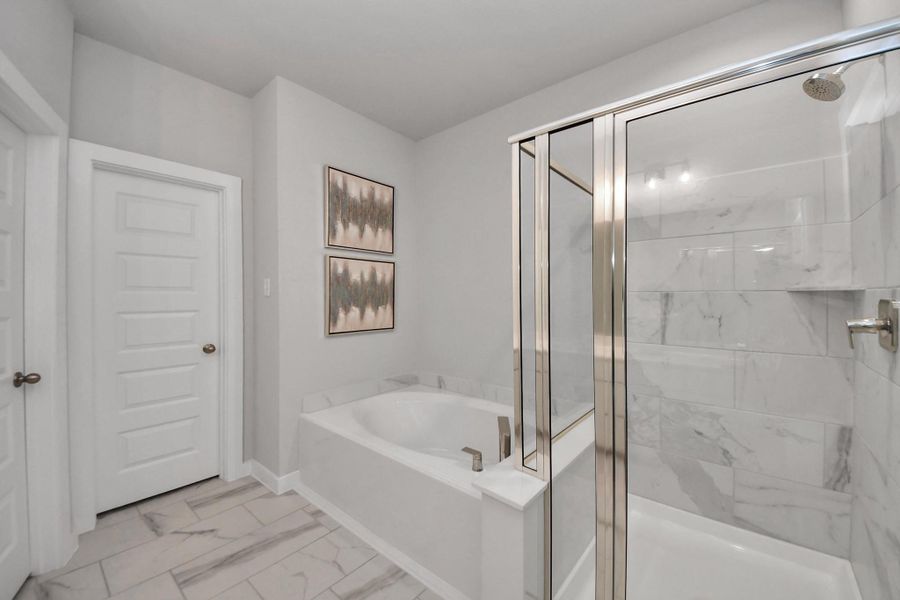 Delight in a spacious walk-in shower enveloped in stylish tile surround, unwind in a separate garden tub adorned with custom detailing. Sample photo of completed home with similar floor plan. Actual colors and selections may vary.