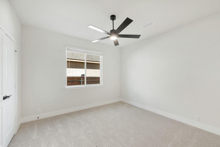 Empty bedroom with carpet flooring, white walls, ceiling fan, and single window